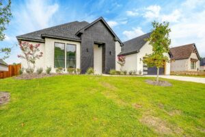 A black and white home with a green lawn.